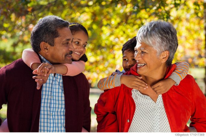 A happy family with grandparents and children enjoying a sunny day outdoors.